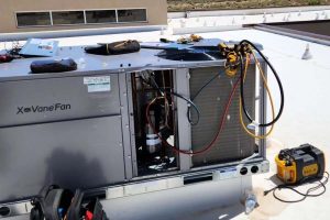 Rooftop HVAC unit repair with tools and gauges on commercial system